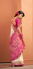Woman wearing a pink and white saree with a floral pattern against a beige background