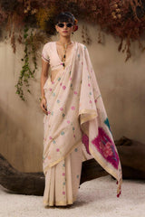 A woman stands elegantly wearing a soft blush pink saree with delicate floral embroidery