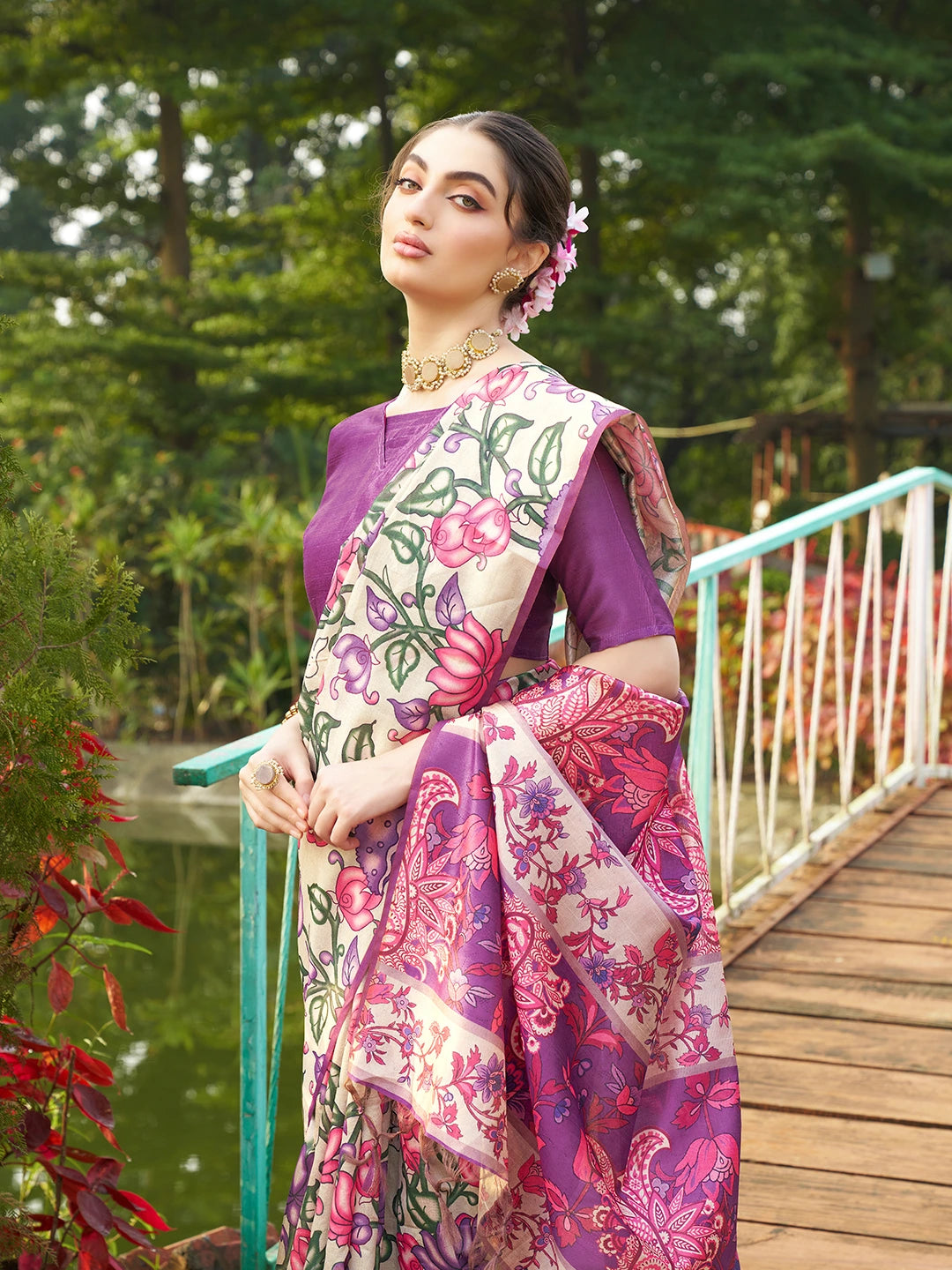 Woman wearing a purple floral printed saree with elegant woven border in a beautiful garden setting