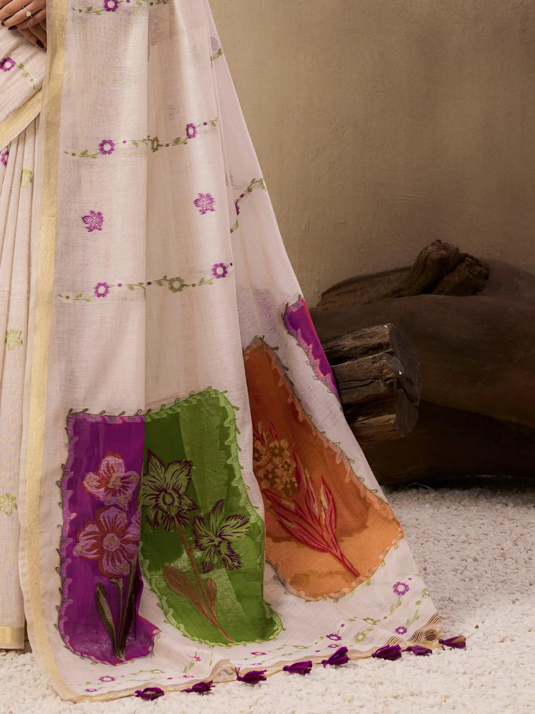 The earthy backdrop with dried hanging plants creates a warm, artistic fashion portrait.
