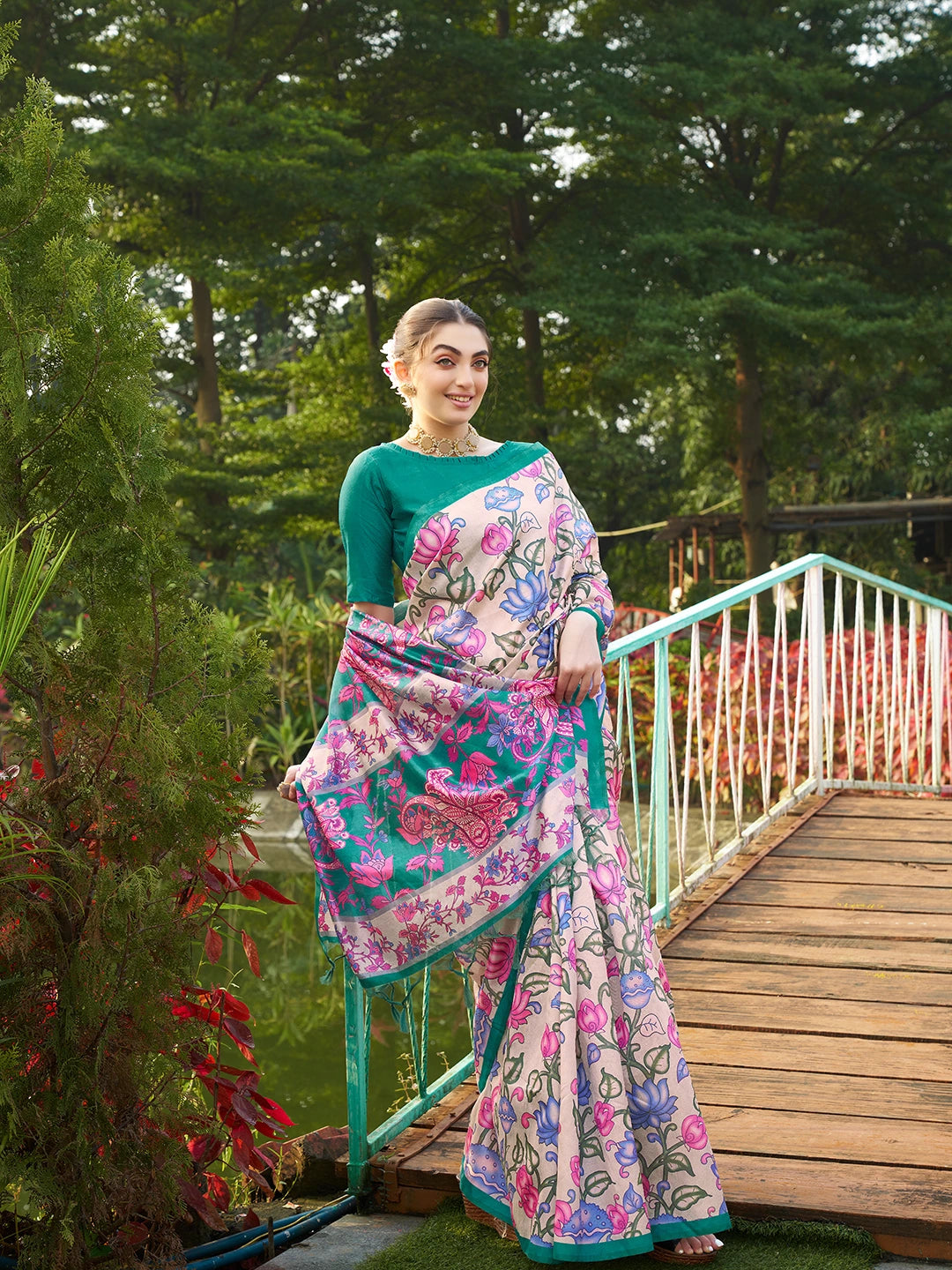 Women's teal green floral saree with decorative woven border and tassel pallu for festive occasions.
