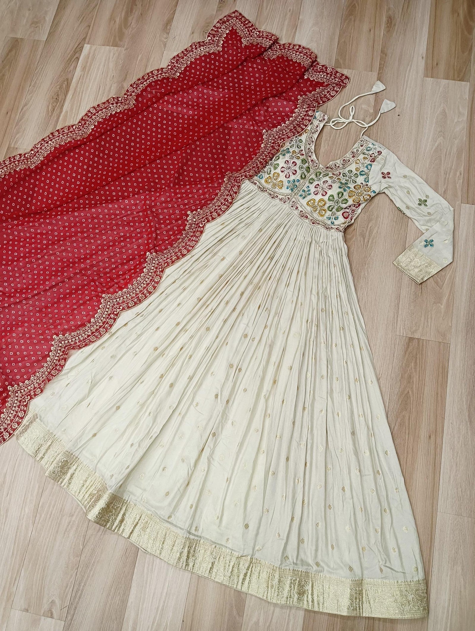 Traditional Indian saree with a red border and embroidered blouse on a wooden floor.