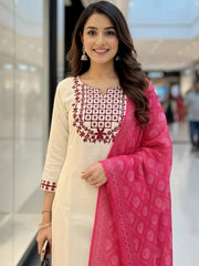 Woman wearing a cream outfit with red and white embroidery and a pink dupatta in a mall setting