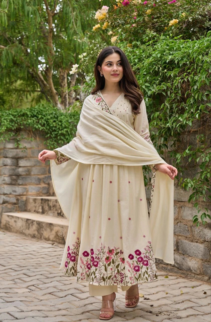 Woman in a traditional outfit with floral patterns standing outdoors.