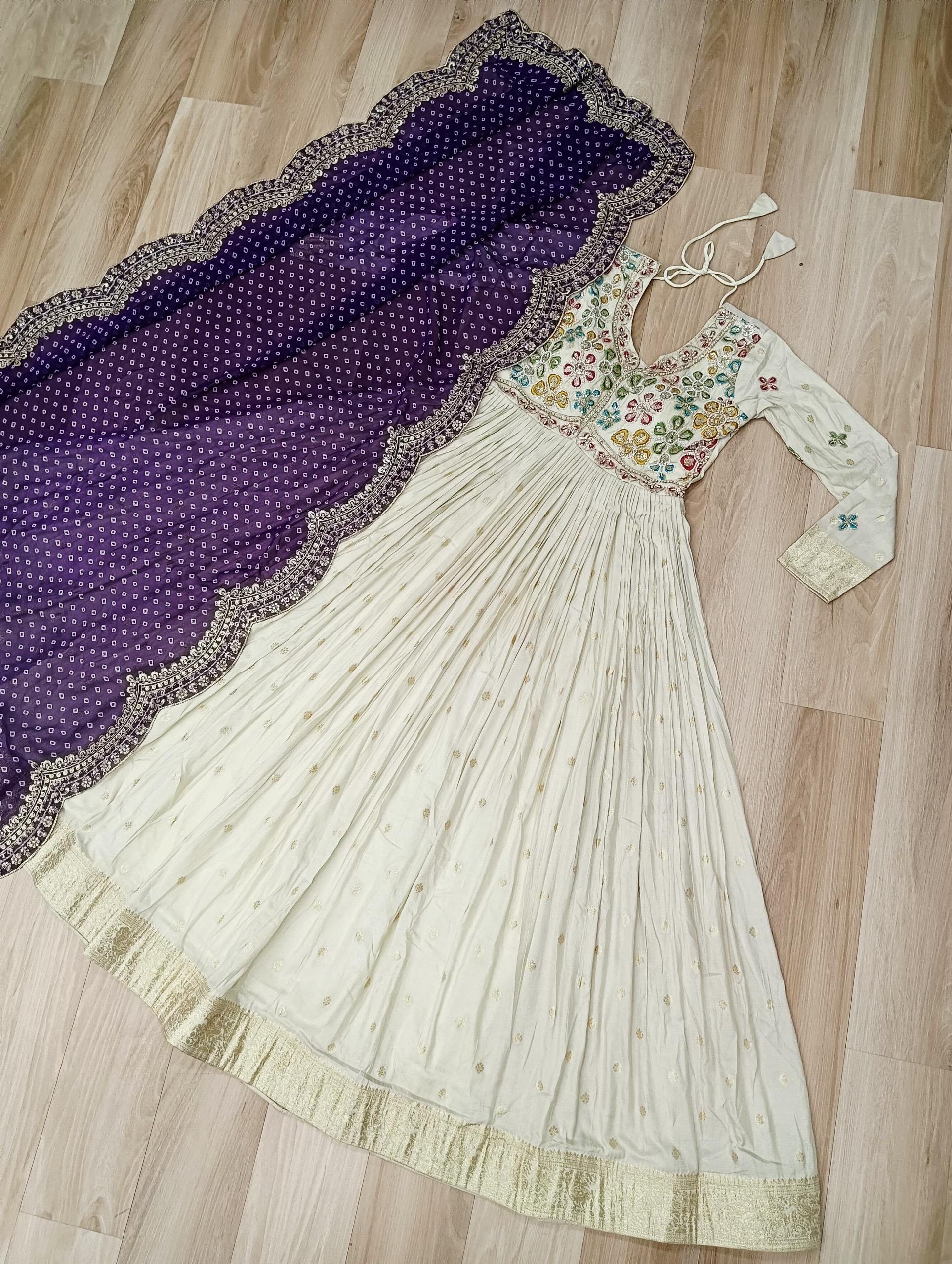 White embroidered dress with a purple and gold dupatta on a wooden floor
