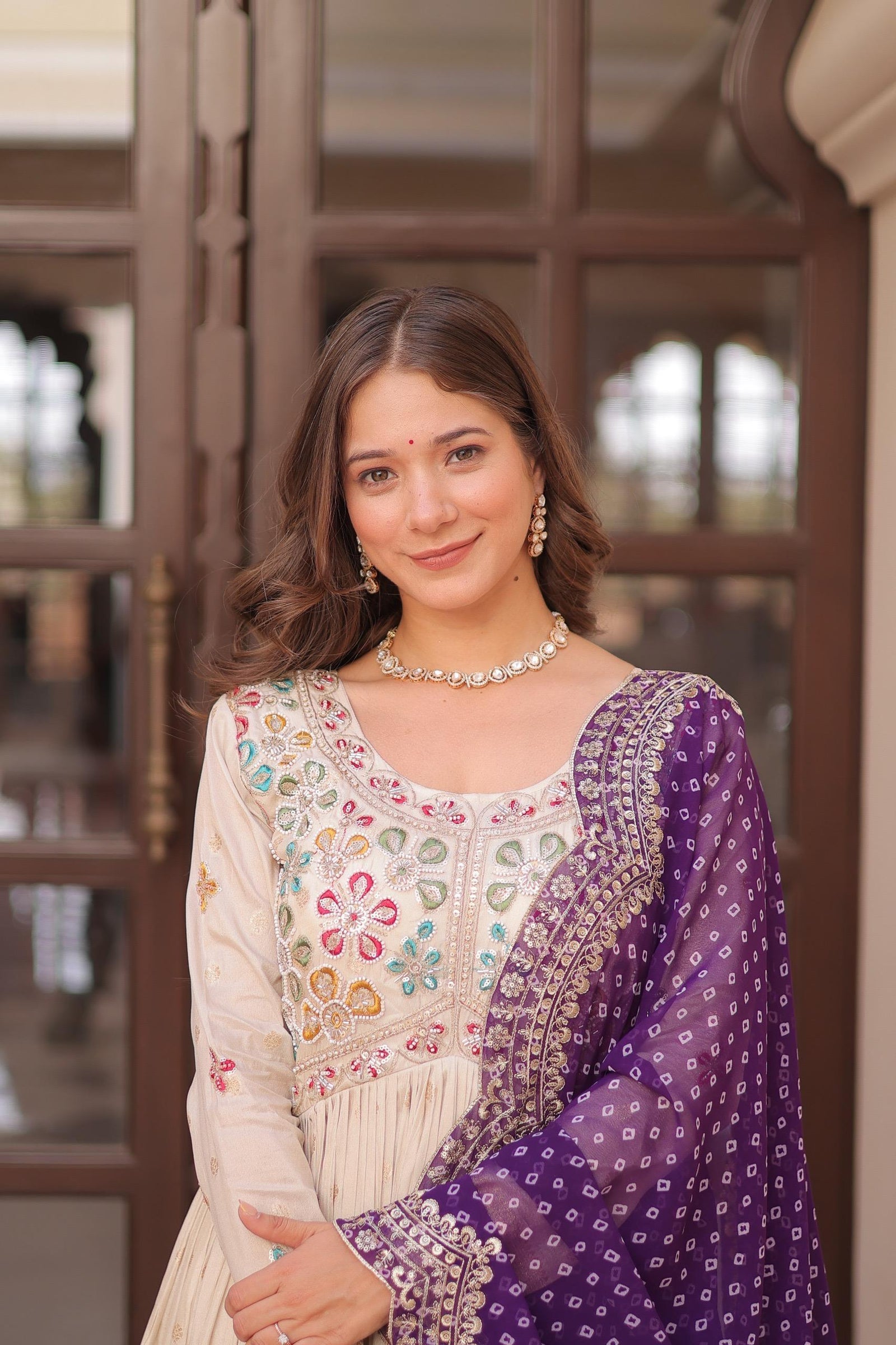 Woman wearing a traditional outfit with a purple shawl in an indoor setting