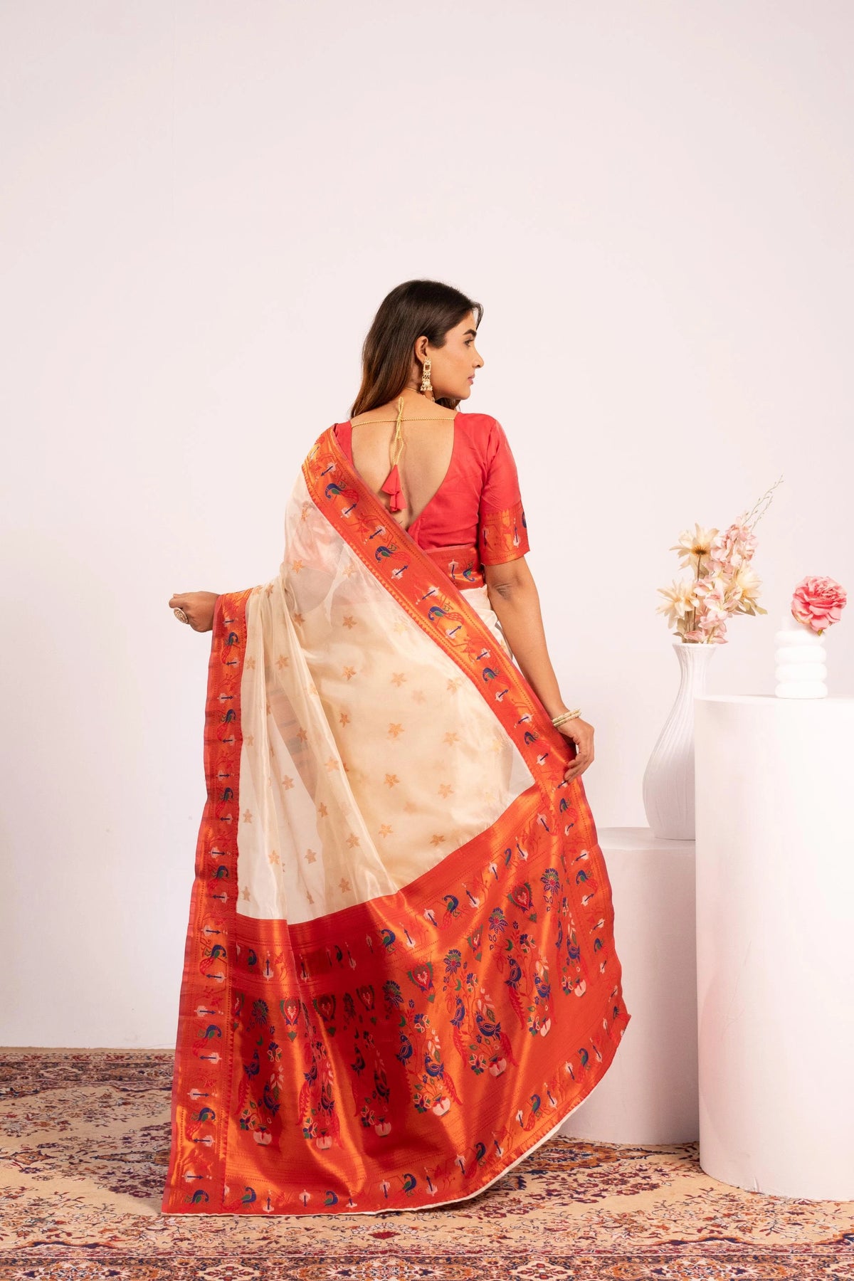 Woman wearing a red and beige saree with a white background