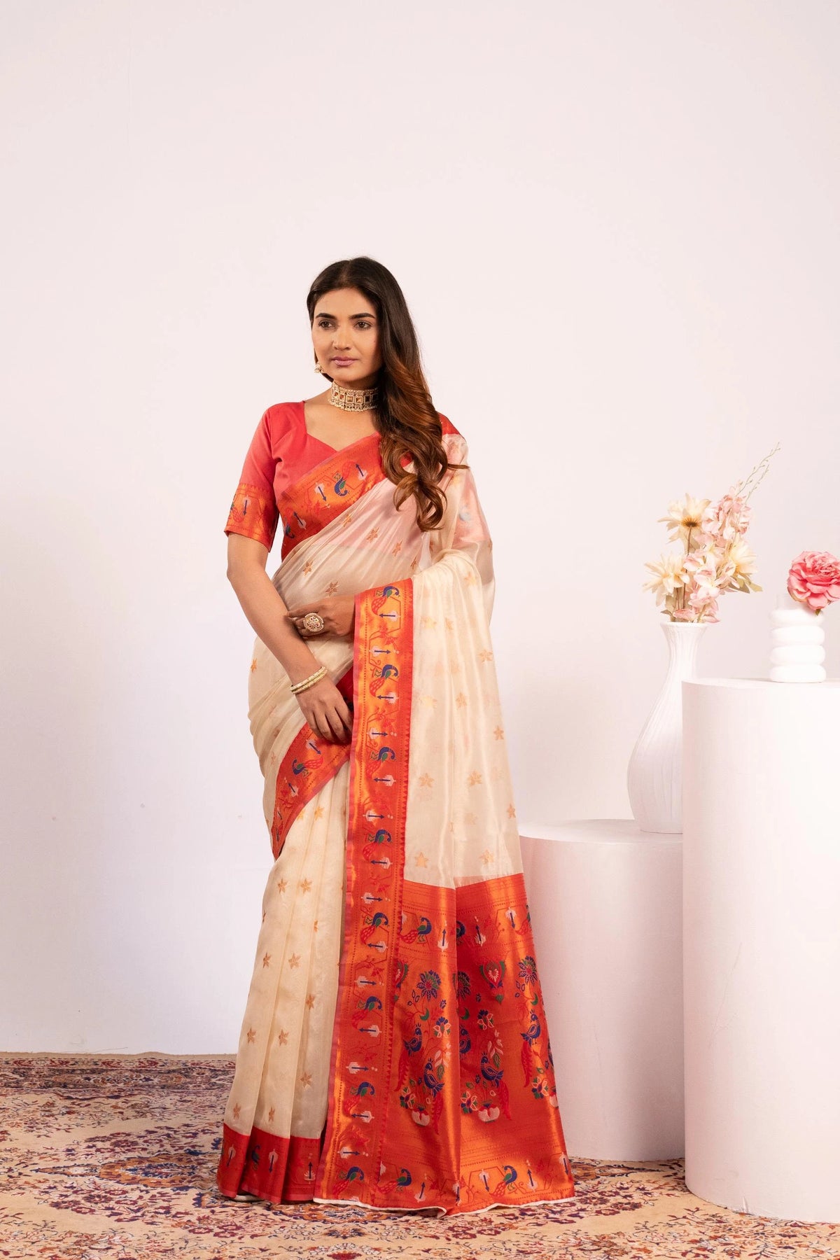 Woman wearing a red and beige saree with a white background