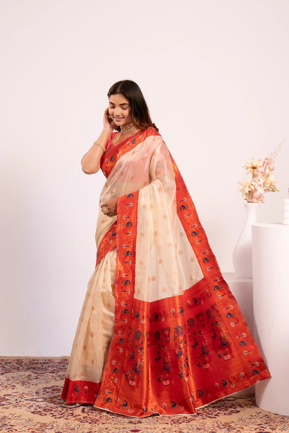 Woman wearing a red and beige saree with a white background