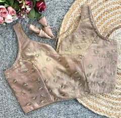 Brown embroidered blouse on a textured surface with flowers and shoes in the background