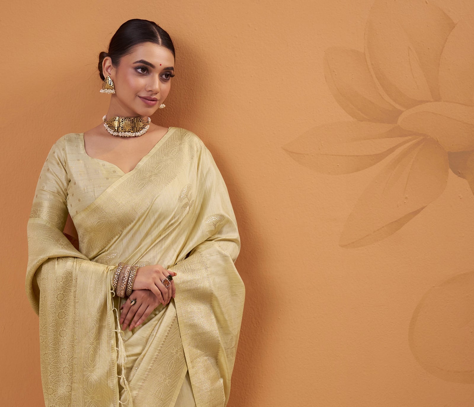 Woman in a light yellow saree against a brown background