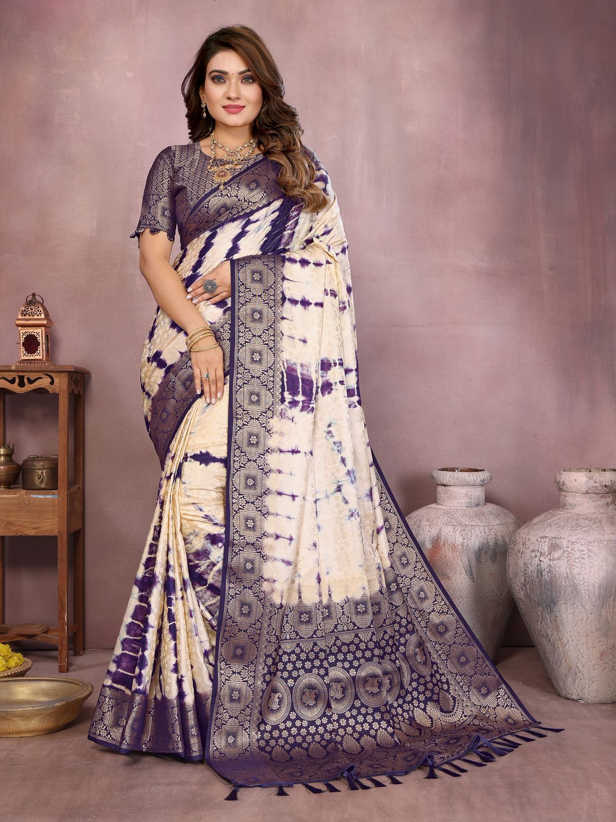 Woman wearing a traditional saree with a purple and white pattern against a neutral background
