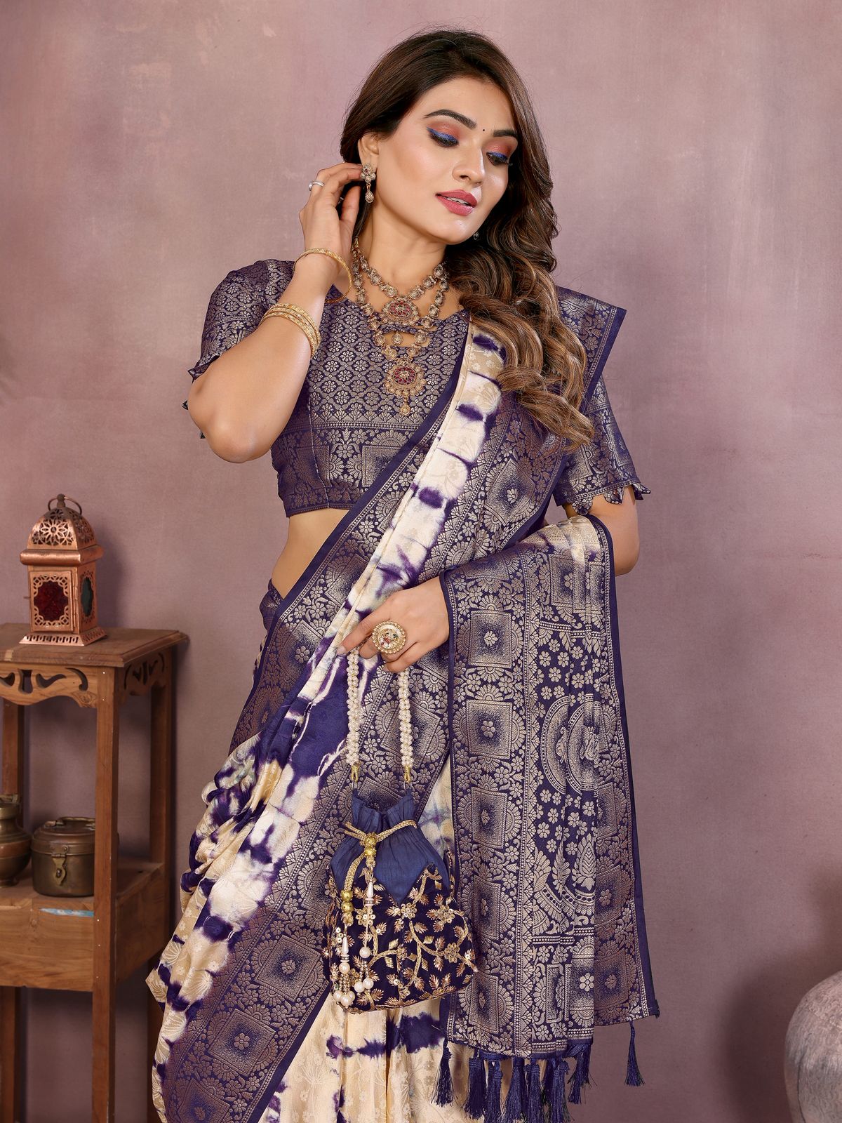 Woman wearing a traditional saree with intricate patterns against a plain background