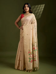 Woman wearing a beige saree with floral patterns on a dark background