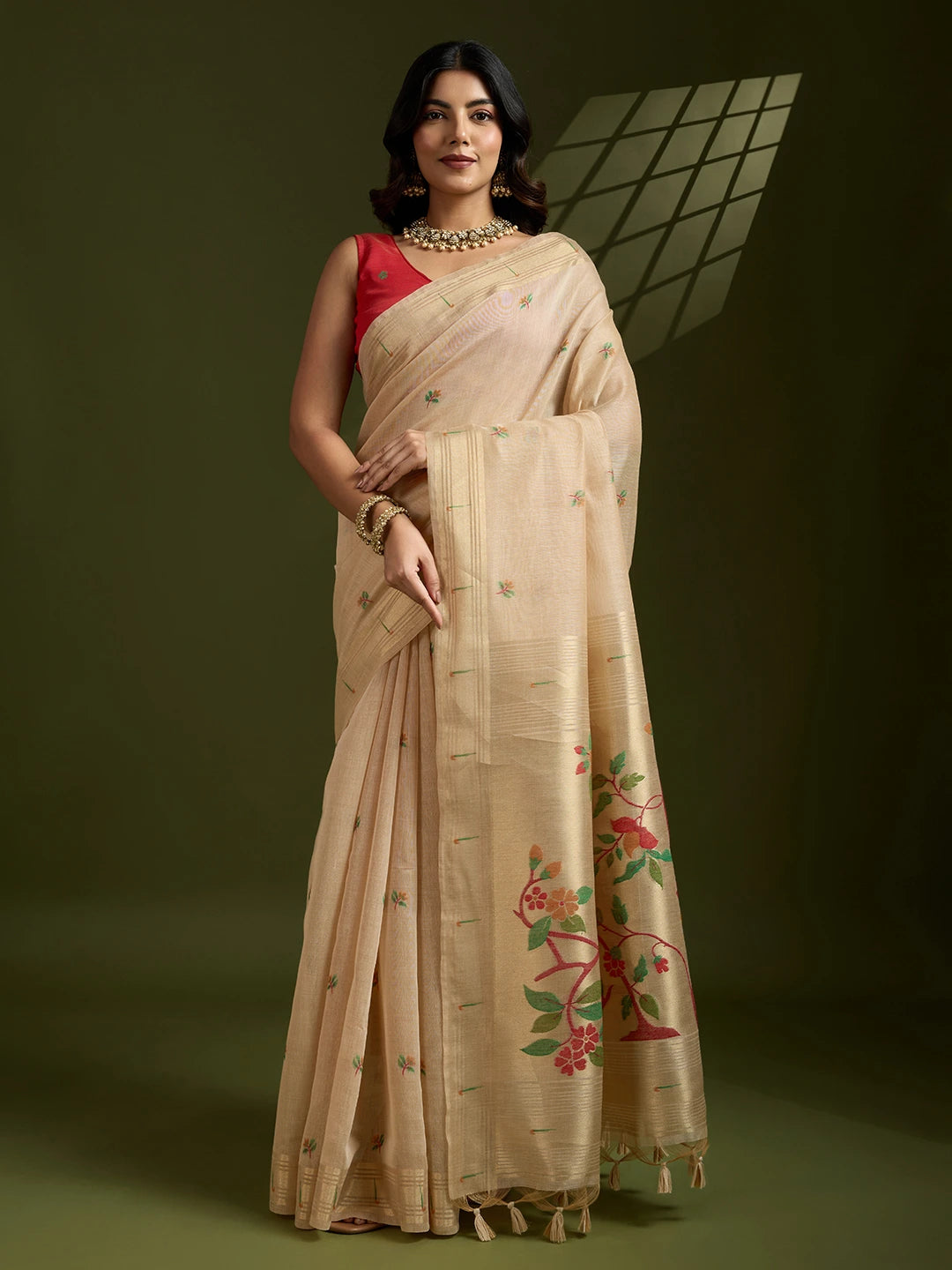 Woman wearing a beige saree with floral patterns on a dark background