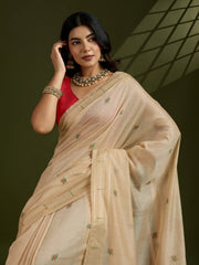 Woman wearing a beige saree with a red blouse against a dark background