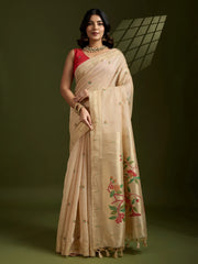 Woman wearing a beige saree with floral patterns on a dark background