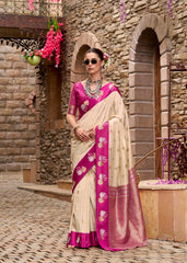 Woman in a pink and white saree standing in front of a stone building.