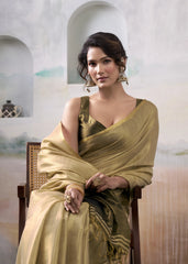 Woman in a gold saree sitting on a chair with a scenic background