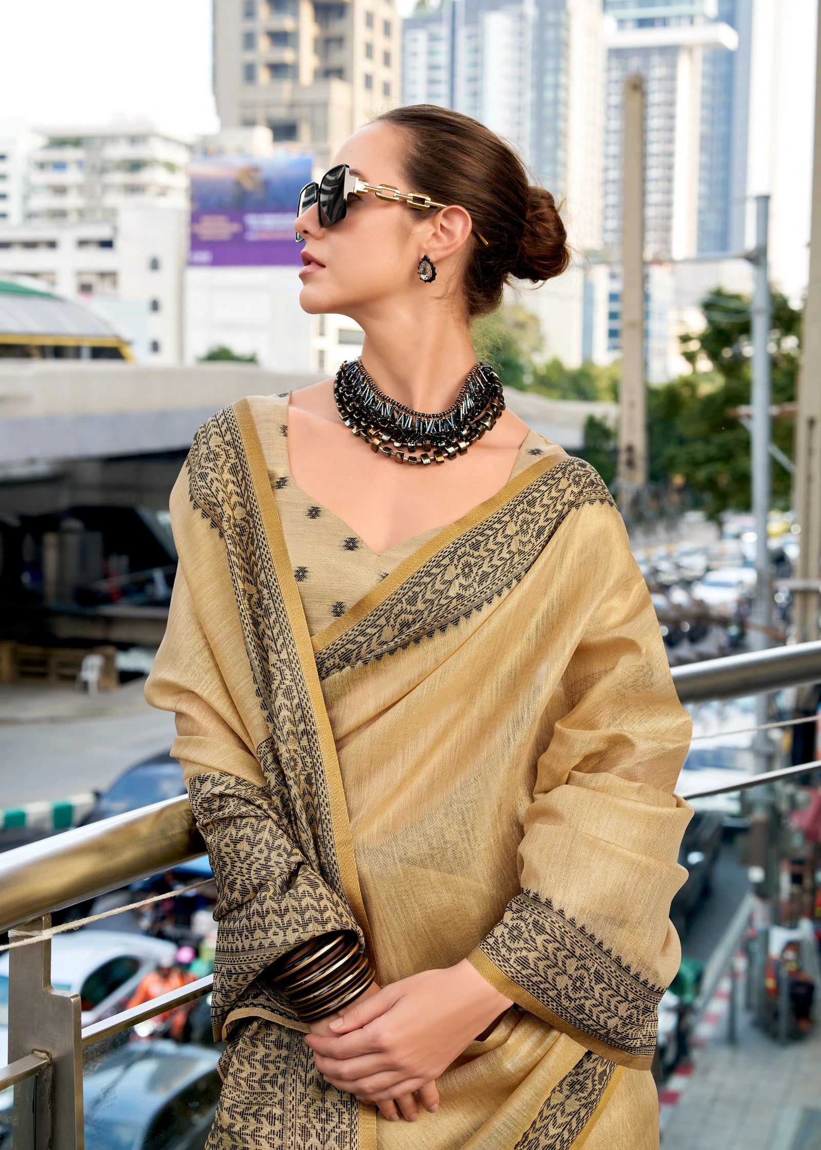 Woman in a beige saree with cityscape background