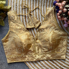 Gold brocade crop top on a textured surface with decorative elements.