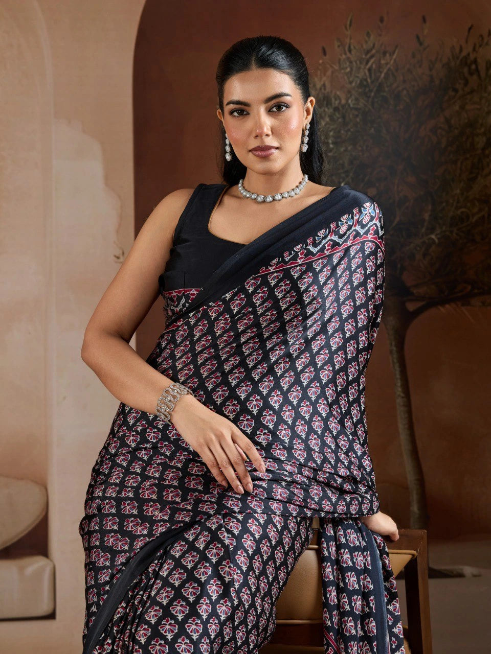 Woman wearing a black and white patterned saree with a plain background