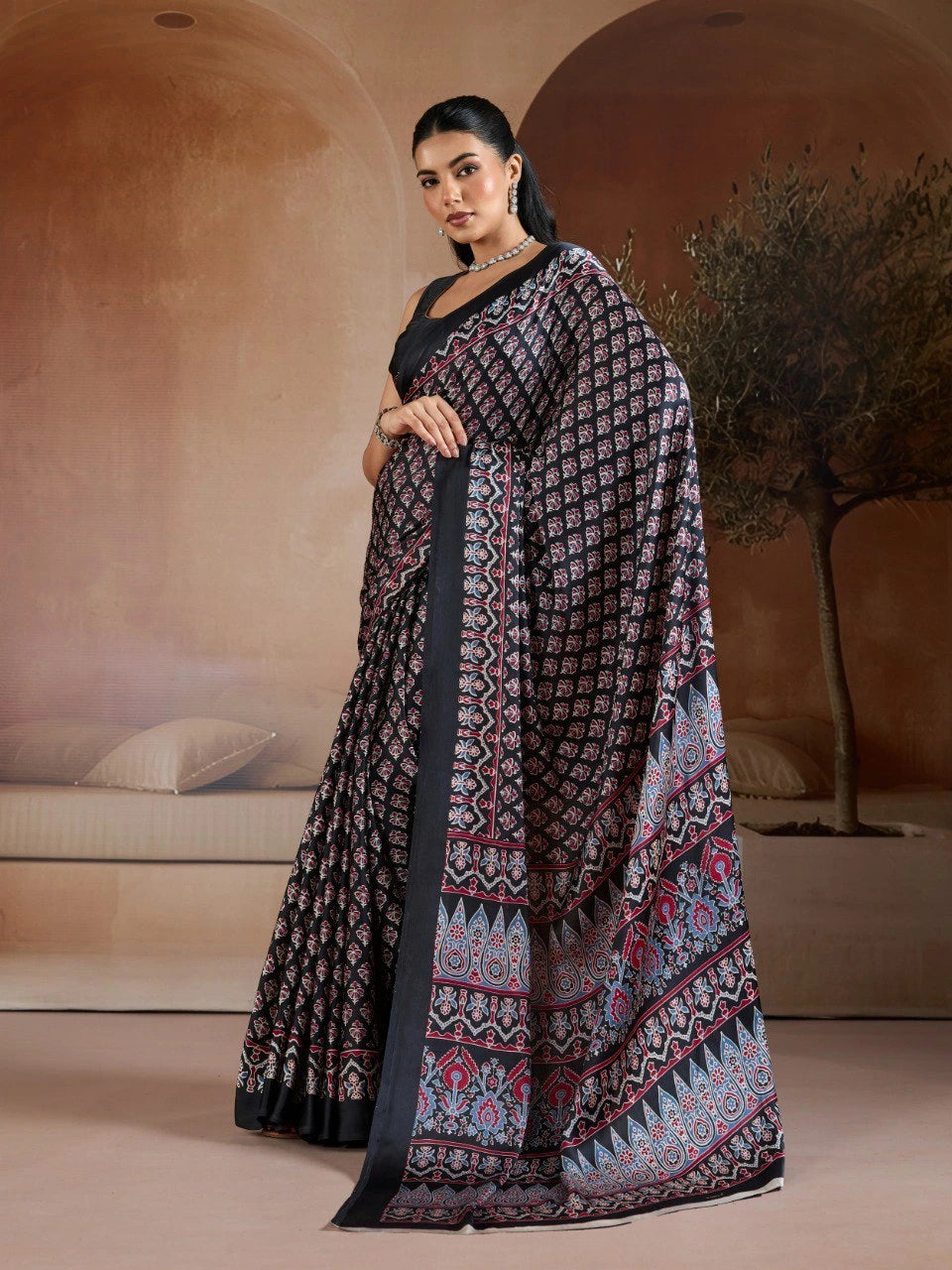 Woman wearing a patterned saree in an indoor setting with neutral colors.