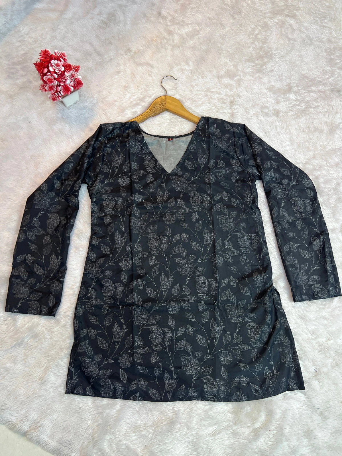 Black floral-patterned dress on a hanger against a light background