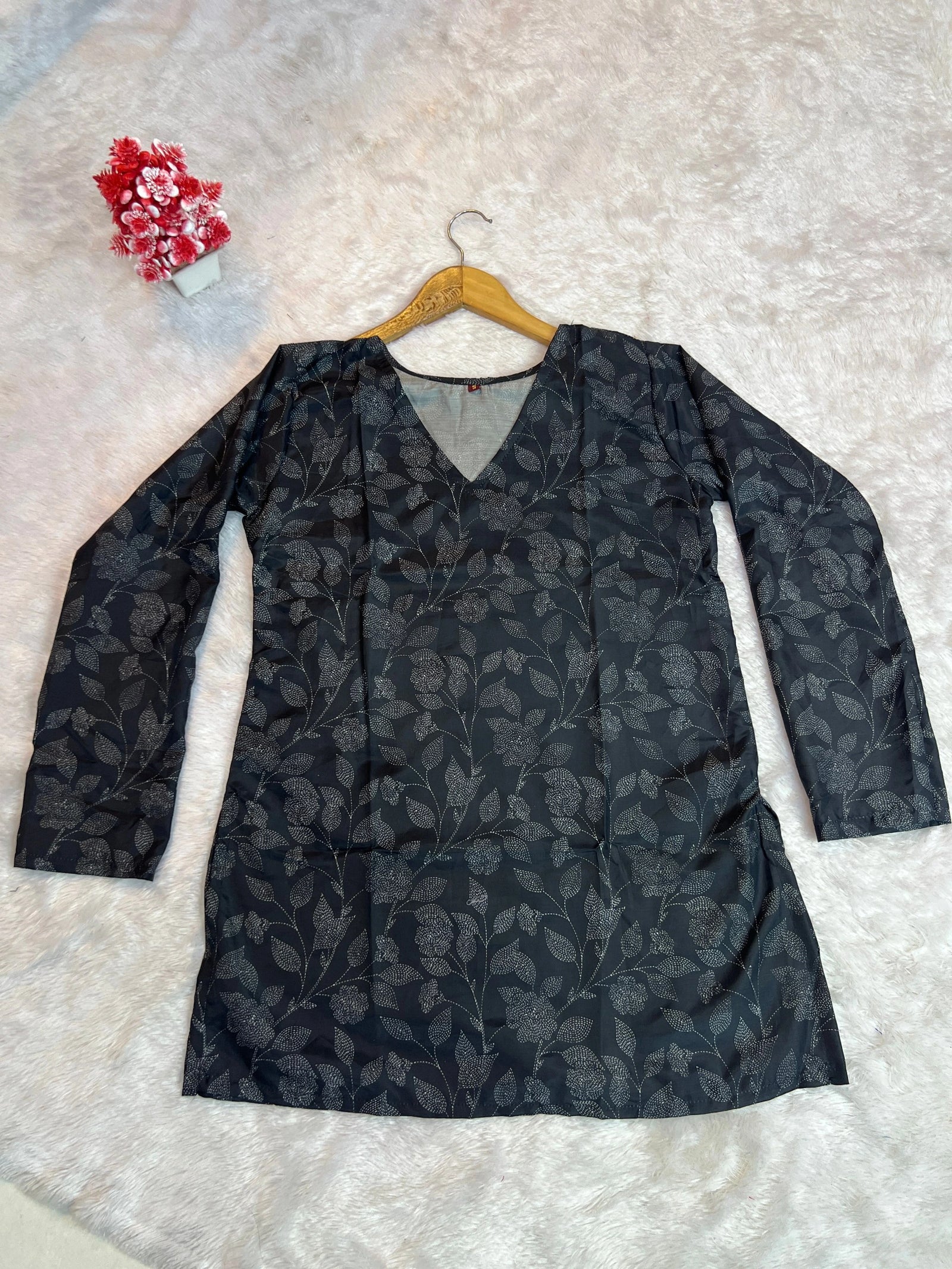 Black floral-patterned dress on a hanger against a light background