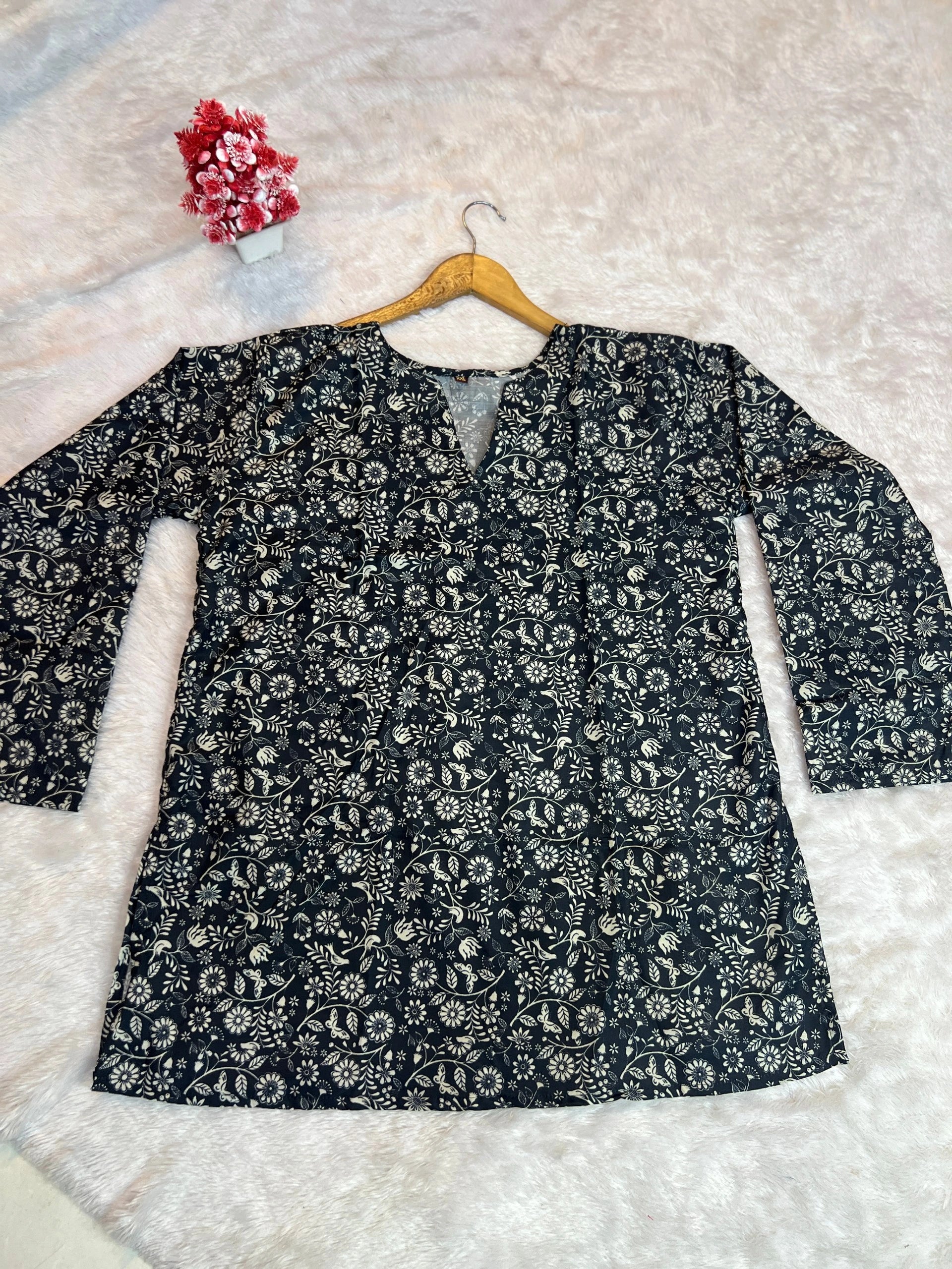 Floral-patterned shirt on a hanger against a textured white background