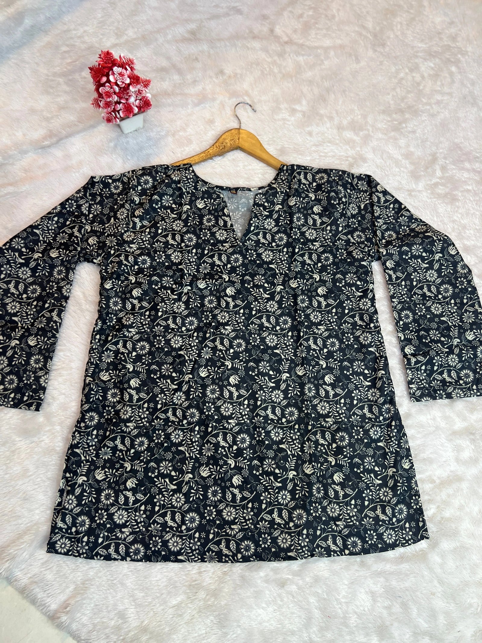 Floral-patterned shirt on a hanger against a textured white background