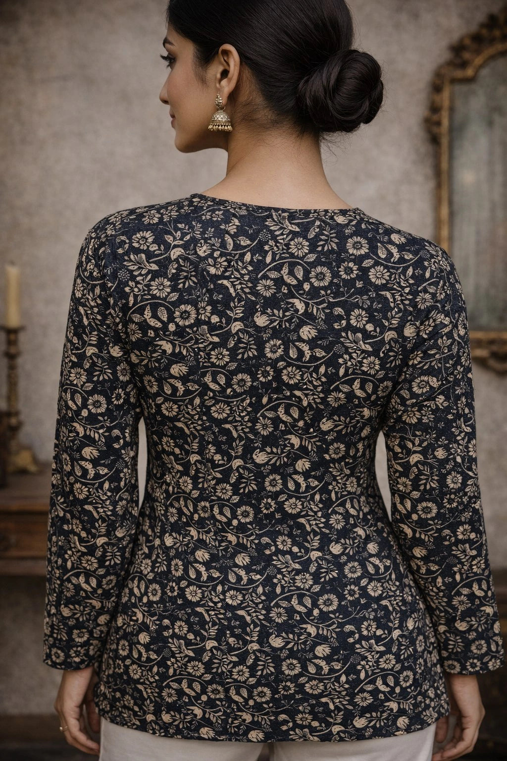 Woman wearing a dark floral patterned top in an indoor setting.