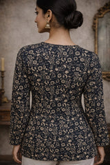 Woman wearing a dark floral patterned top in an indoor setting.