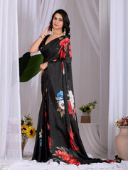 Woman wearing a black saree with floral patterns against a white curtain background