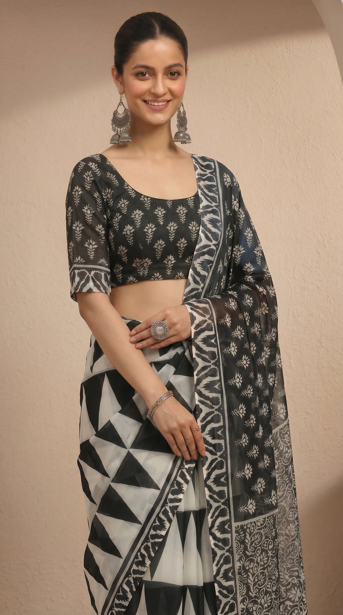 Woman wearing a black and white patterned saree against a beige background