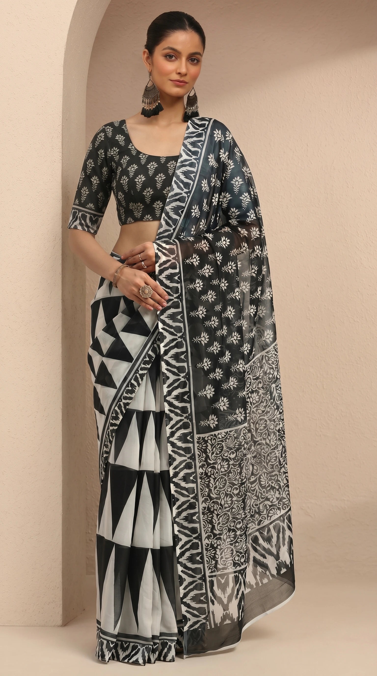Woman wearing a black and white patterned saree against a beige background