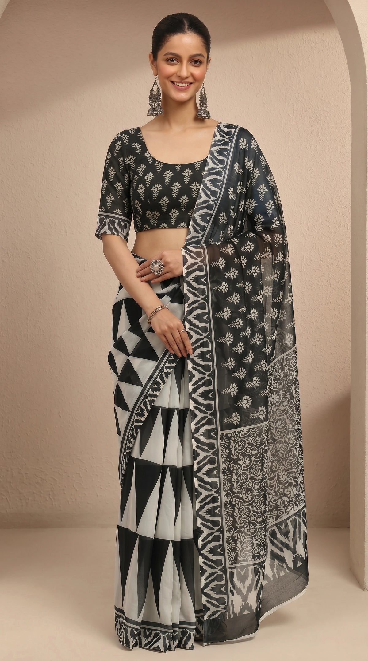 Woman wearing a black and white patterned saree against a beige background