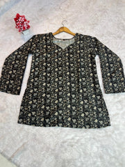 Floral-patterned top on a hanger against a textured white background