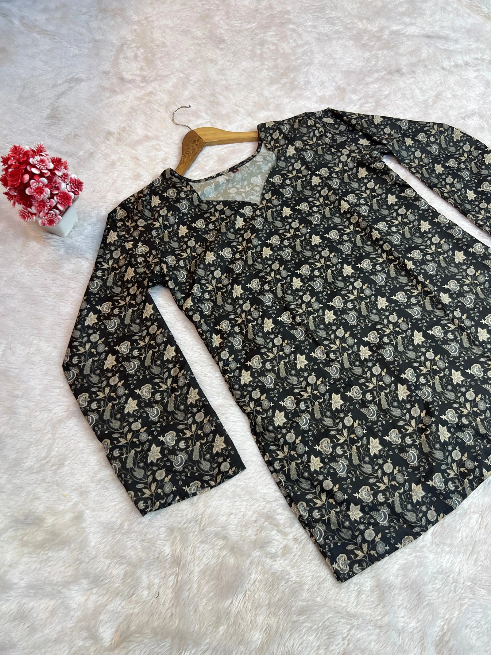 Floral-patterned shirt on a hanger against a textured white background