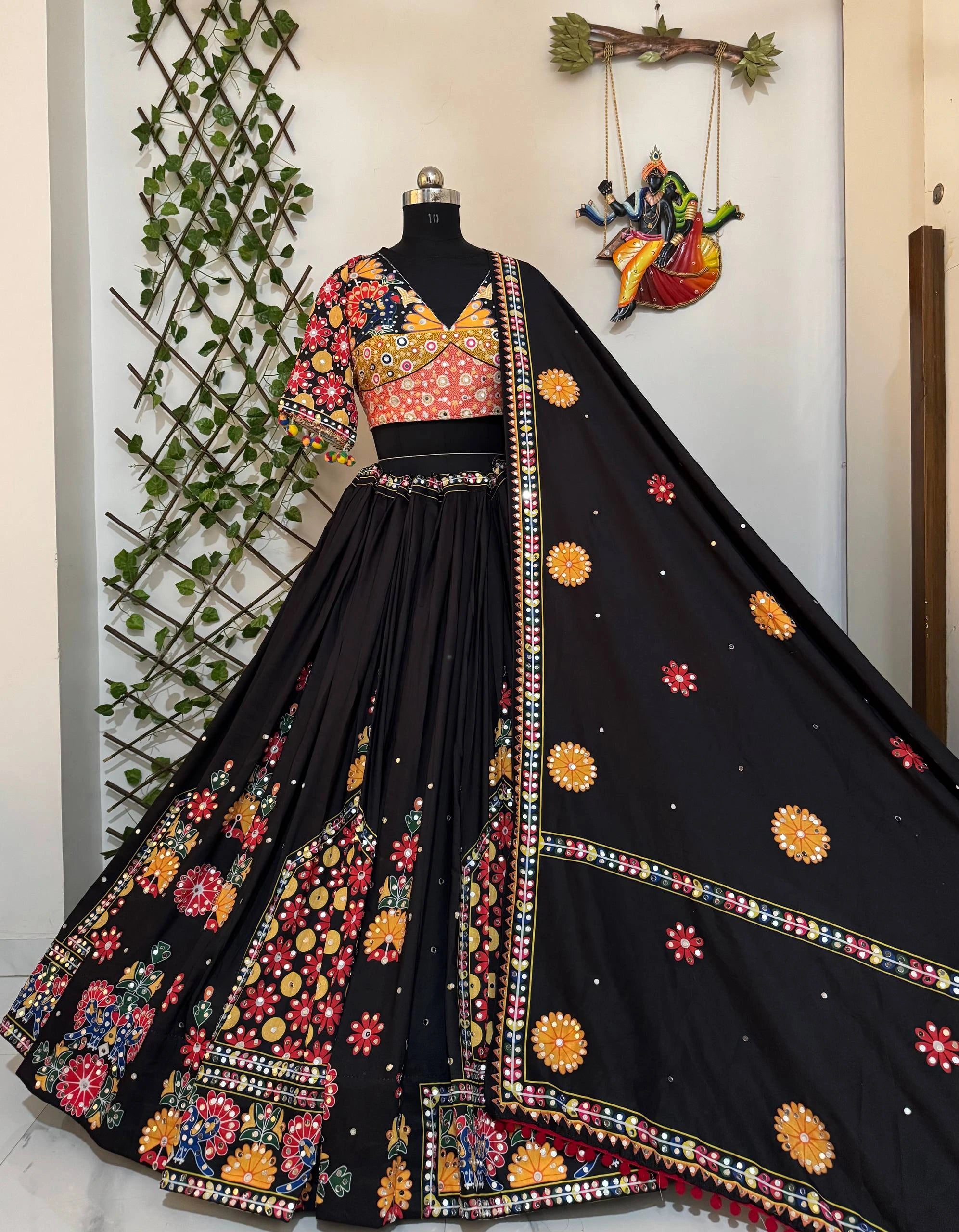 Black embroidered saree with colorful patterns on a mannequin against a decorative wall.