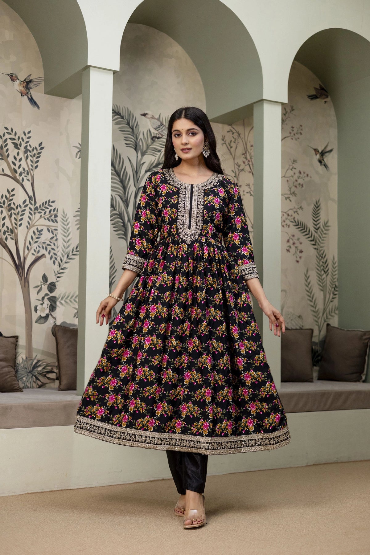 Woman wearing a floral dress in an indoor setting with decorative walls.