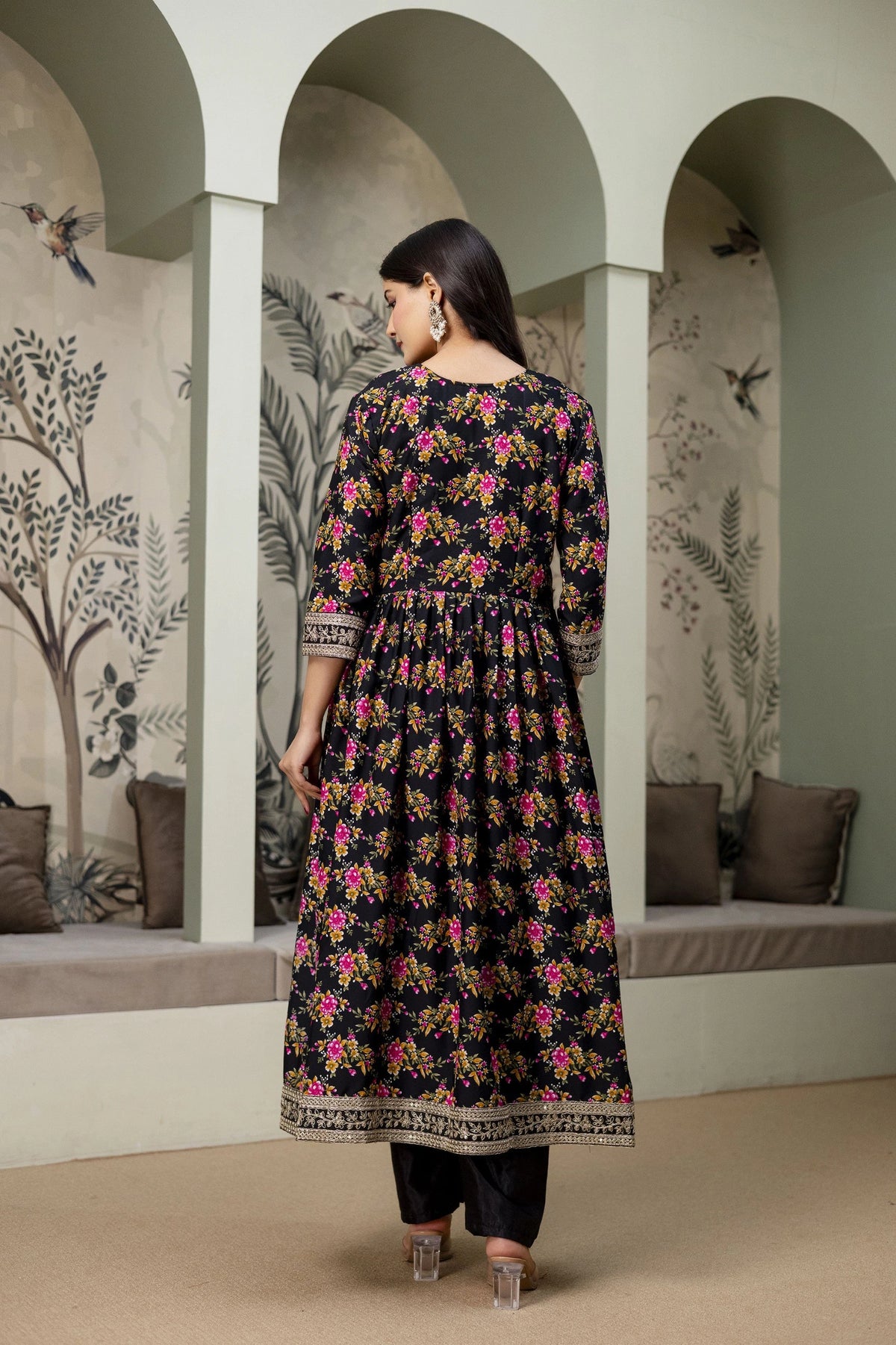 Woman wearing a floral dress in an archway with decorative walls.