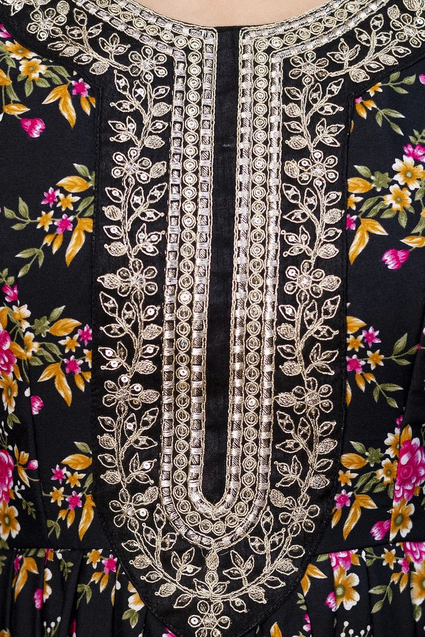 Close-up of a black garment with floral patterns and intricate silver embroidery.