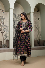 Woman in a floral dress standing in an arched room with decorative walls.