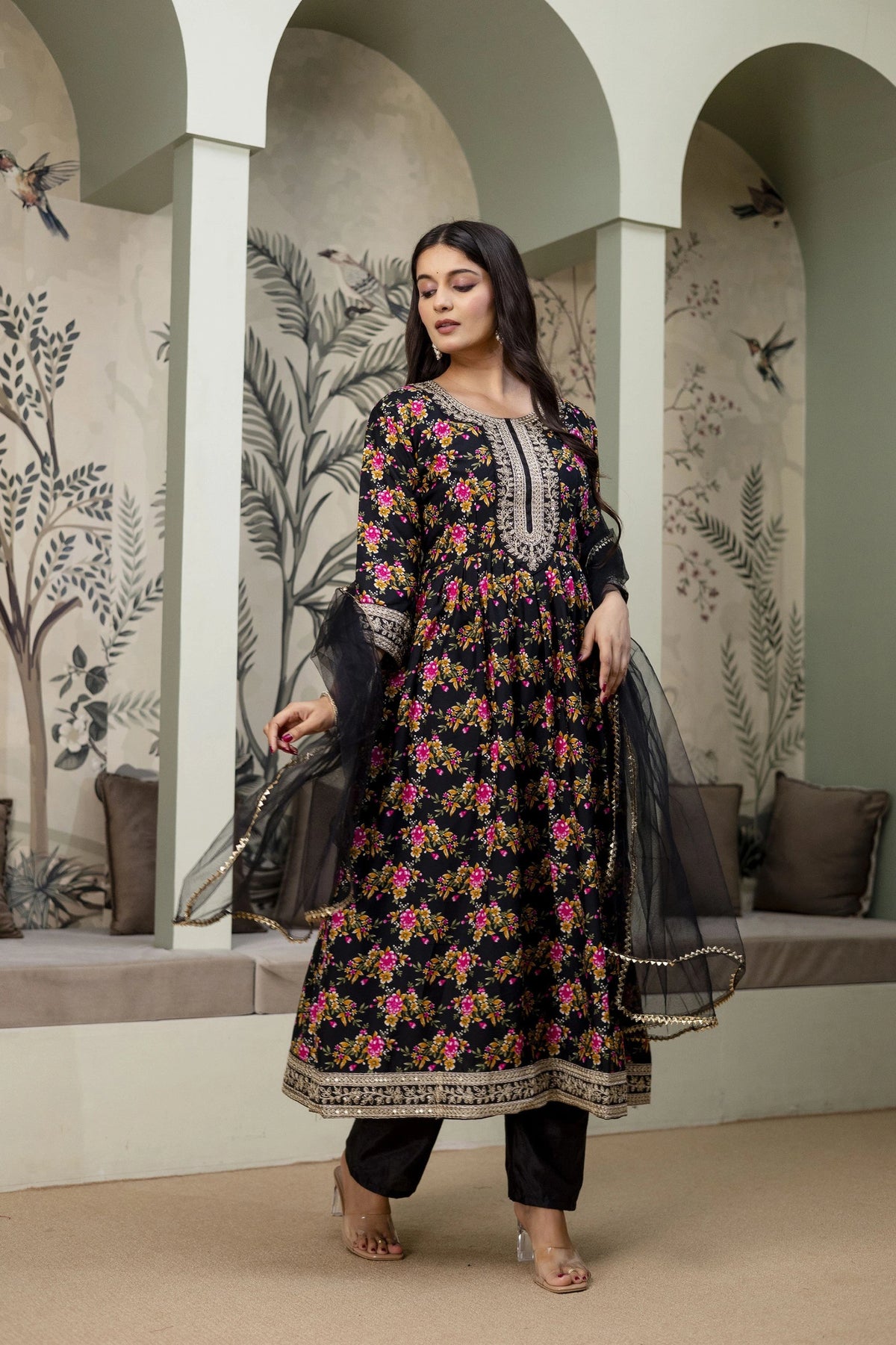 Woman in a floral dress standing in a decorative interior setting