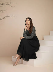 Woman sitting on steps wearing a black and white patterned top and black skirt.