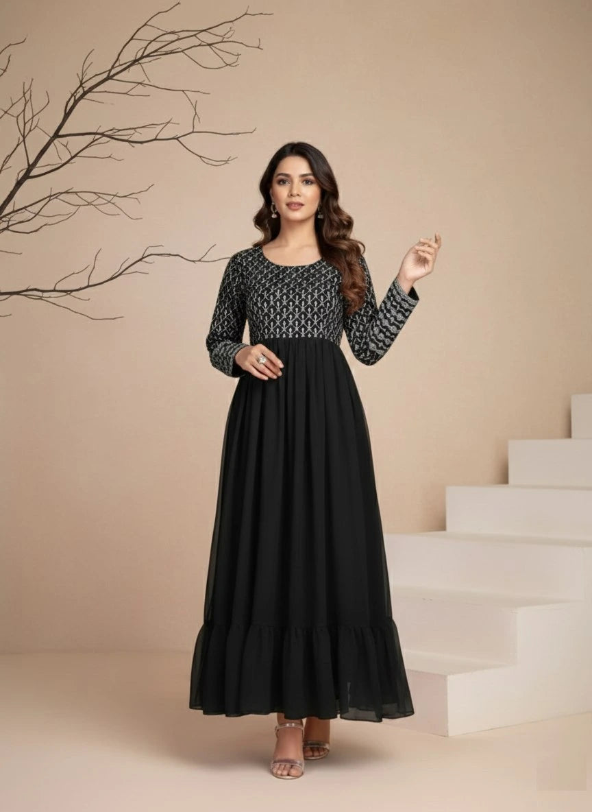 Woman in a black dress standing on a staircase with a beige wall and branch in the background