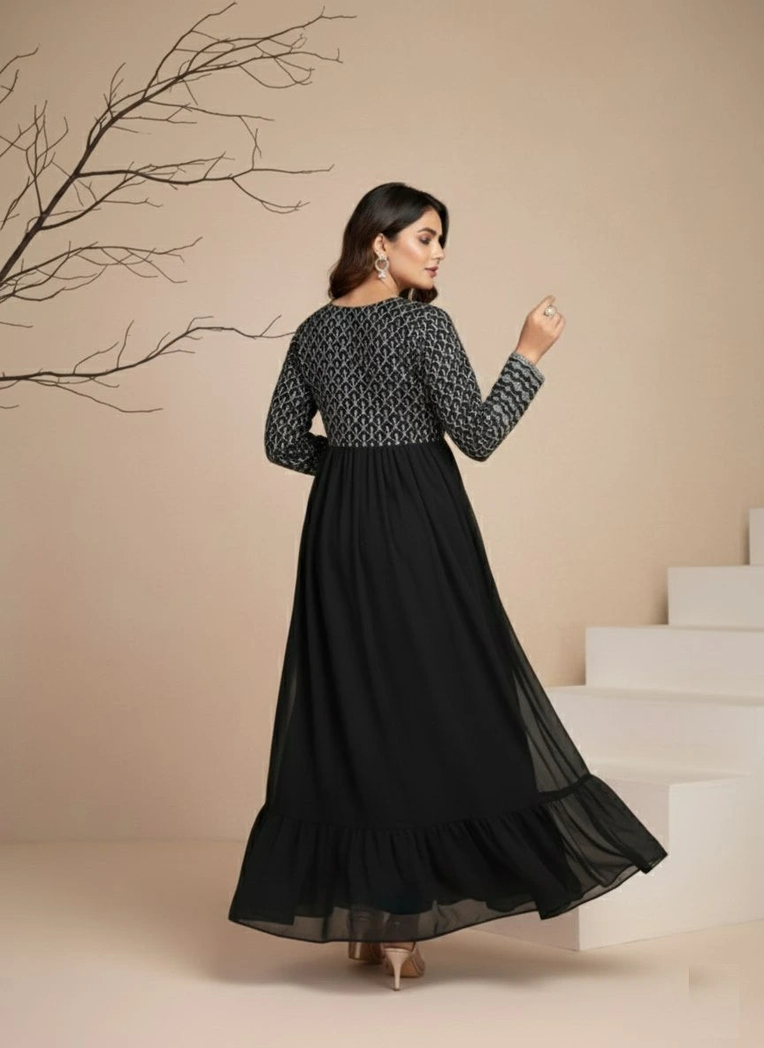 Woman wearing a black and white patterned top with a long black skirt in a minimalistic setting.