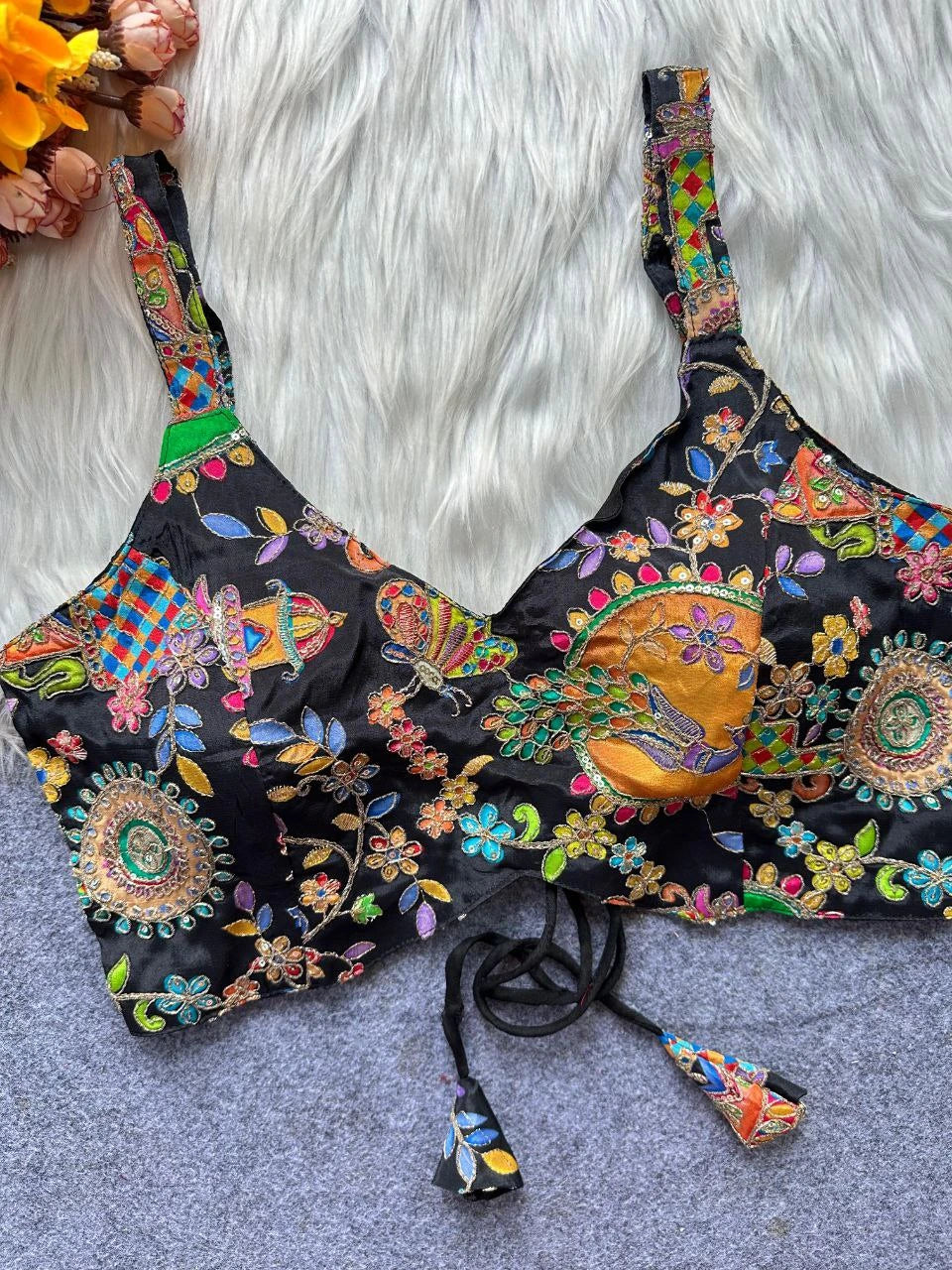 Colorful embroidered lingerie set on a textured surface with flowers in the background