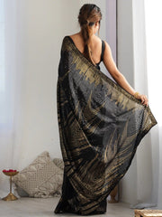 Woman holding a black and gold patterned scarf in a minimal indoor setting.